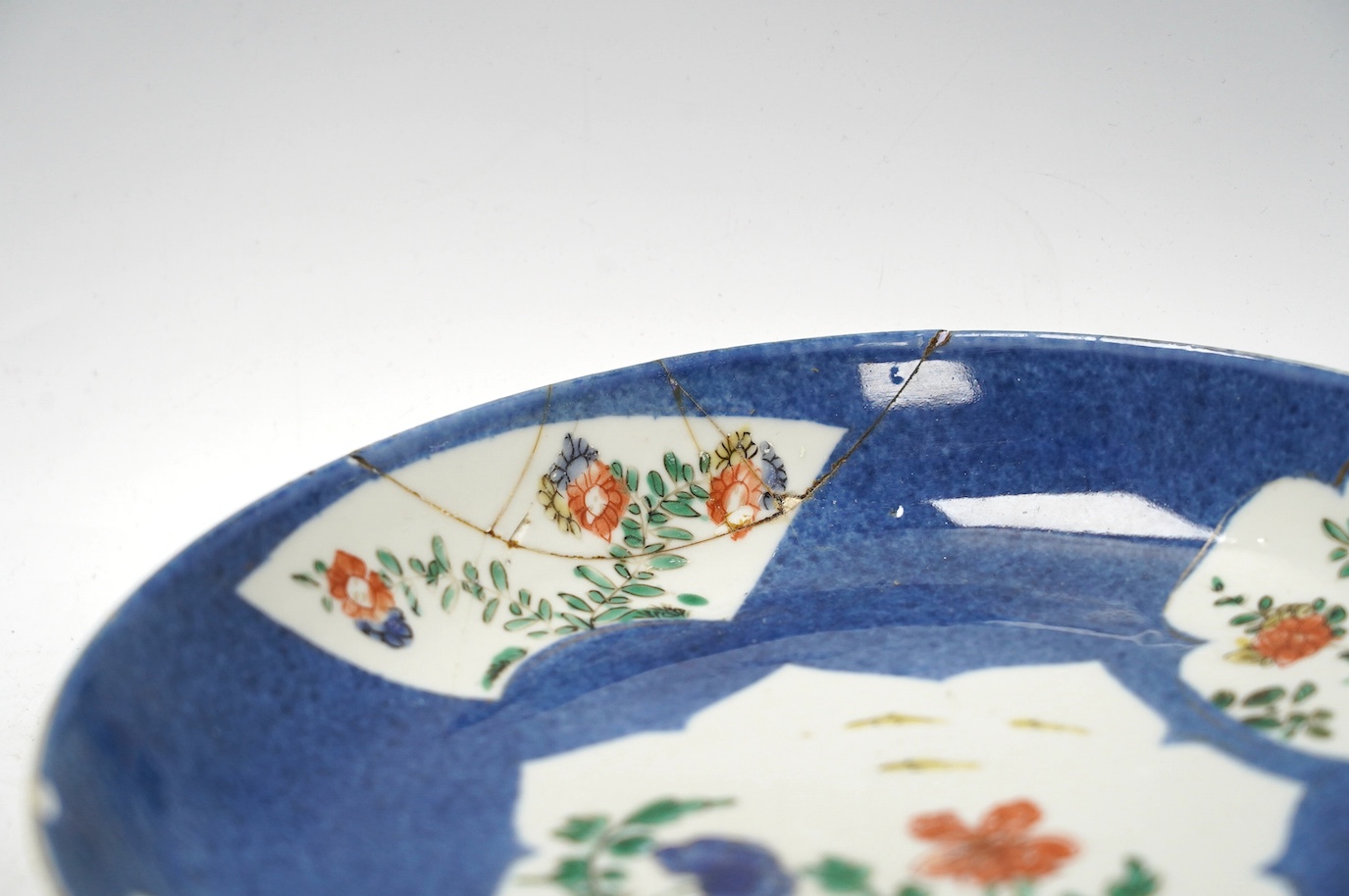 A Chinese powder blue famille verte dish, Kangxi period, a Yongzheng Imari plate and a Kangxi blue and white saucer, largest 22cm diameter. Condition - poor
